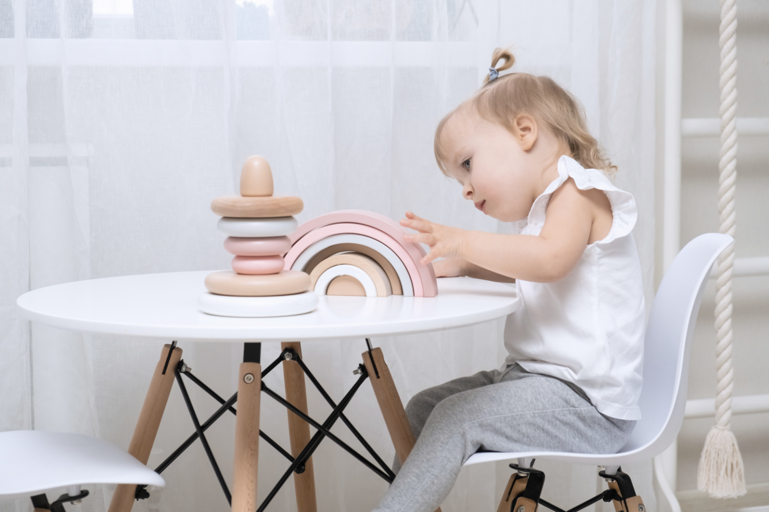 Child girl playing with a wooden toys at table. Little cute girl with natural toys