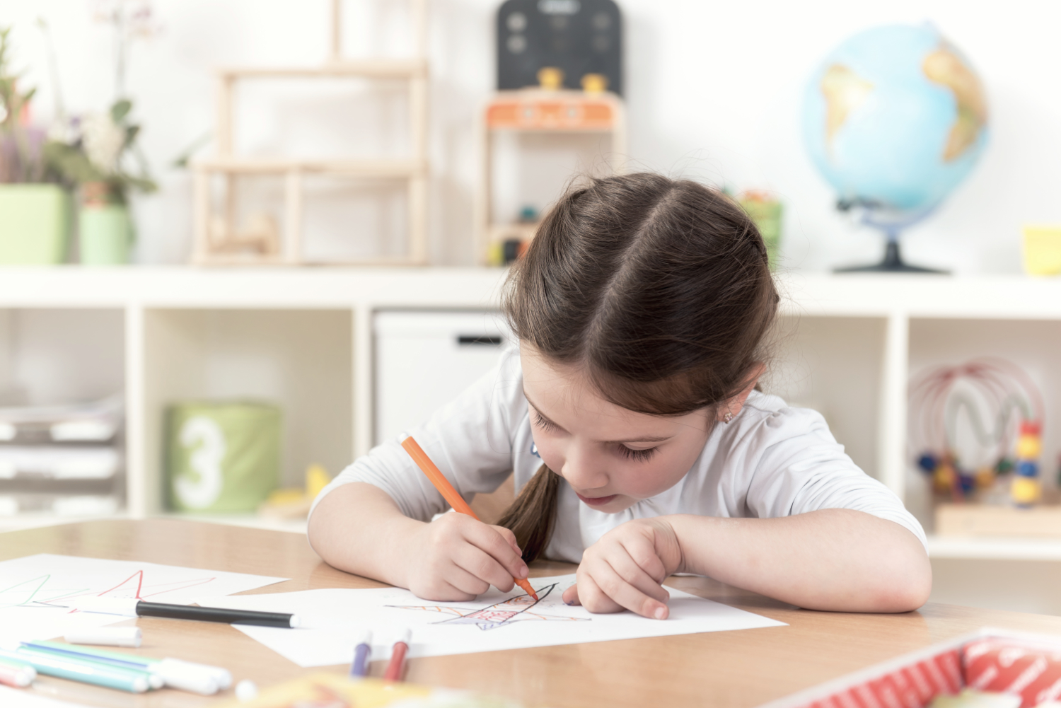 cute little girl drawing with felt-tip pen in kindergarten class