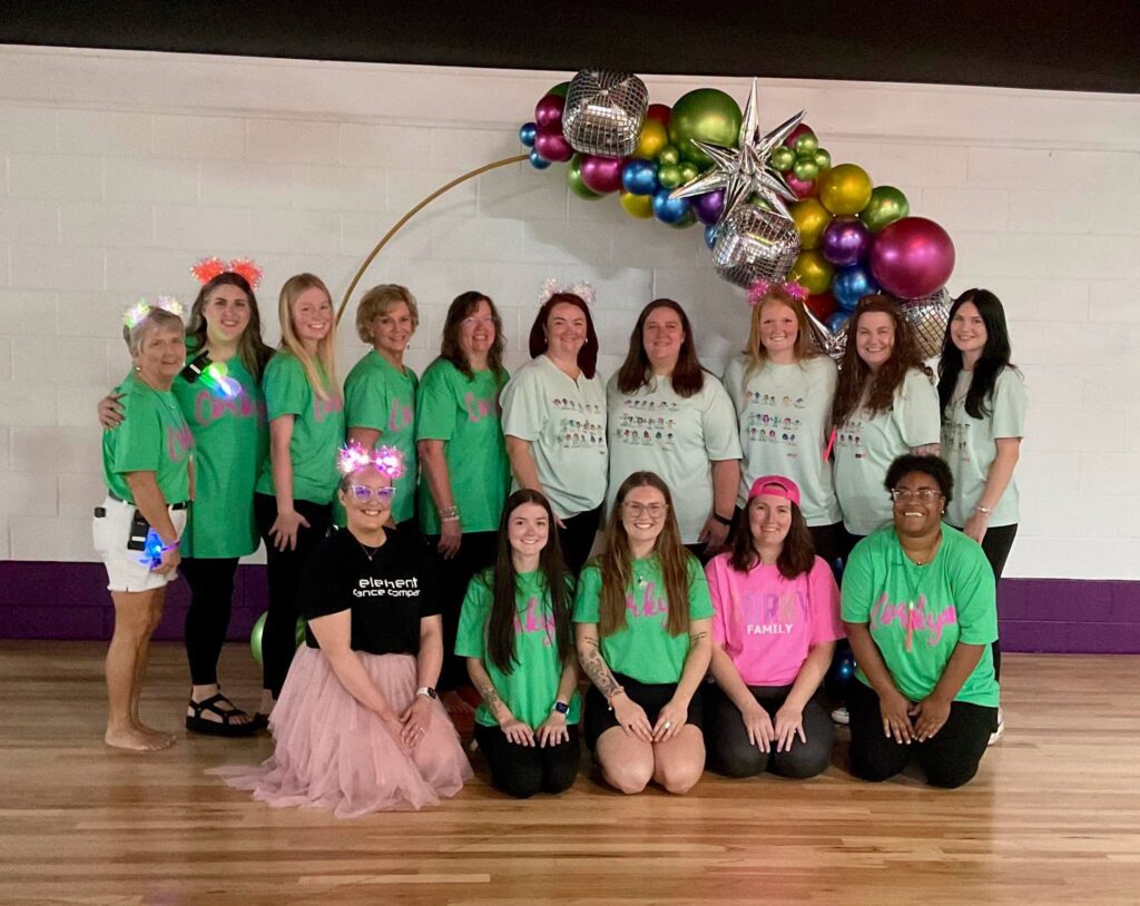 The Corky team gathered together in matching shirts in front of a colorful balloon arch