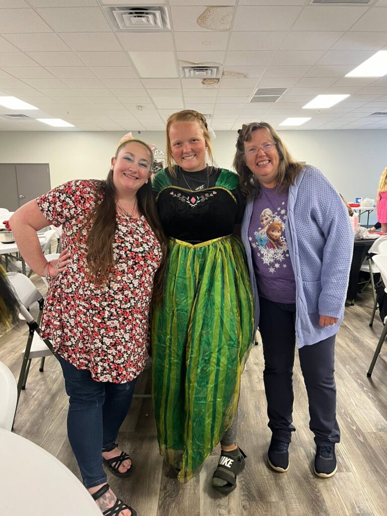 Three Corky team members smiling together at a staff event, one dressed in costume