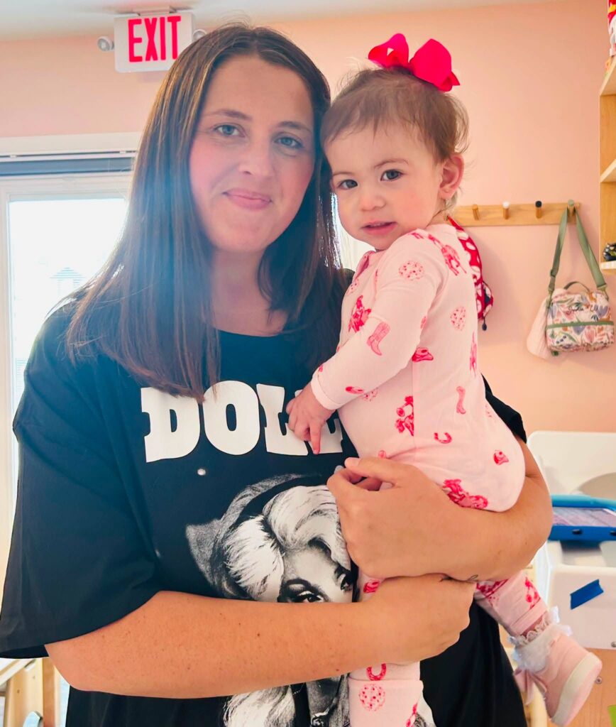 Celena Trussell, Infant 2 Teacher at The Corky Magnolia, holding a smiling little one